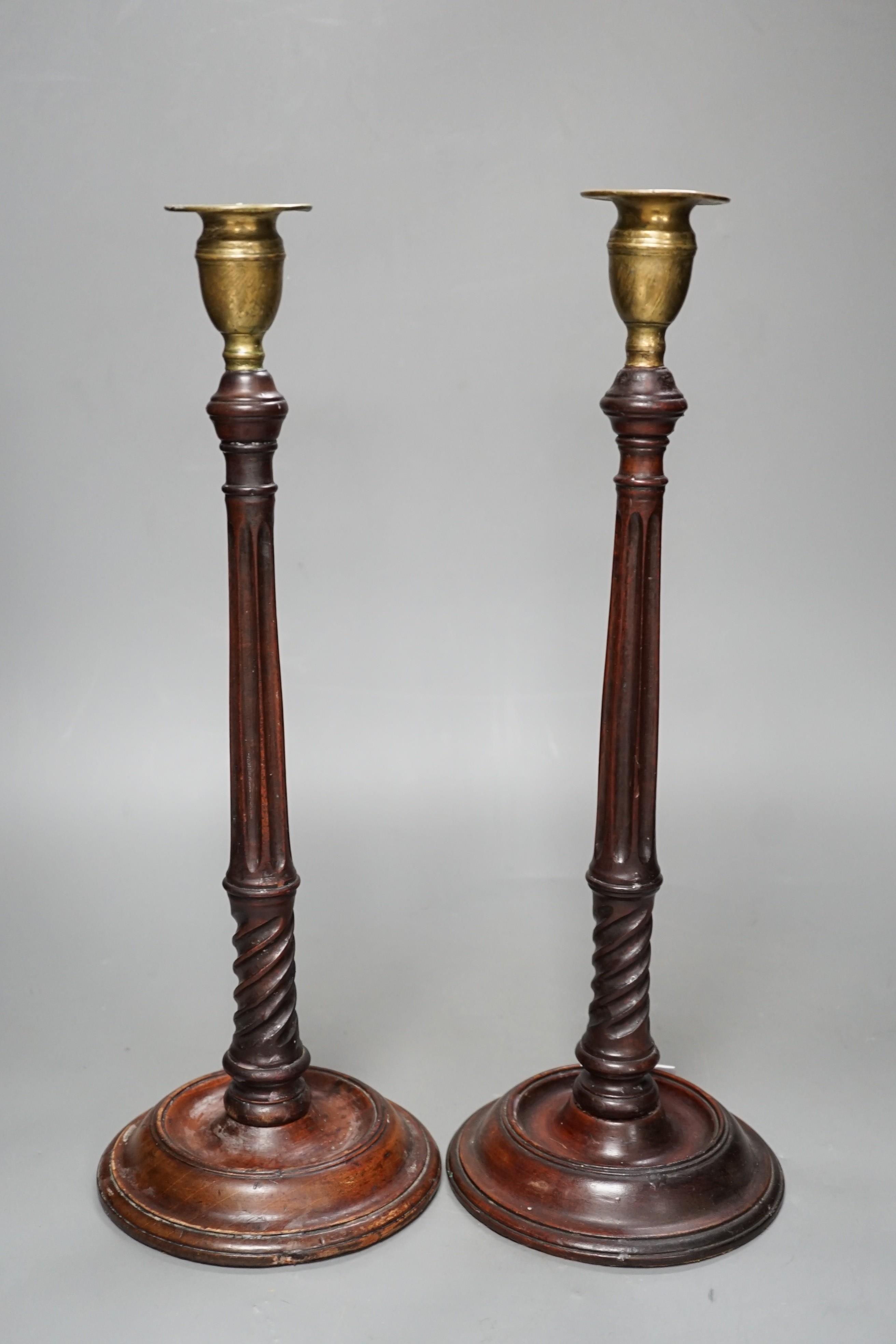 A pair of George III style carved mahogany candlesticks, with brass sconces, 38cms high